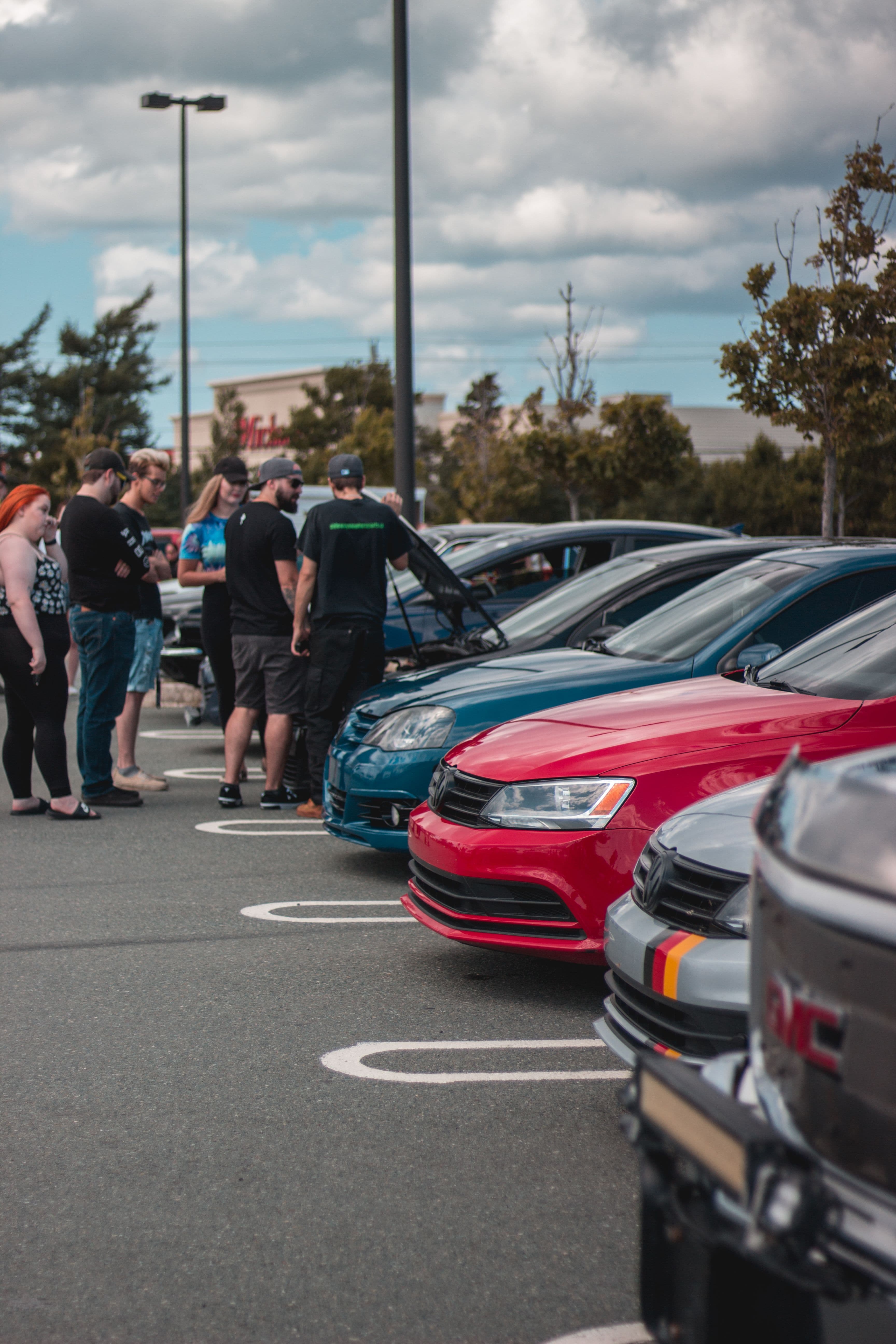 A group of enthusiasts gathered around modified cars at a casual meetup